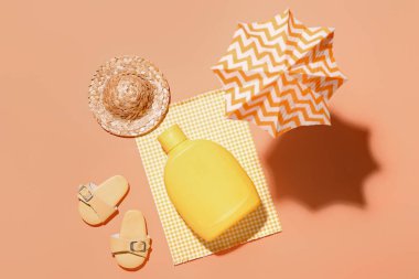 Turuncu arka planda güneş kremi ve plaj aksesuarları ile yaratıcı kompozisyon