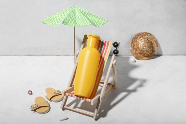 Plaj aksesuarlarıyla yaratıcı kompozisyon ve duvarın yanındaki beyaz masada güneş kremi.