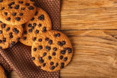 Tahta arka planda çikolata parçalı lezzetli kurabiyeler.