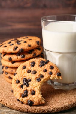 Çikolata parçalı lezzetli kurabiyeler ve masada bir bardak süt, yakın plan.