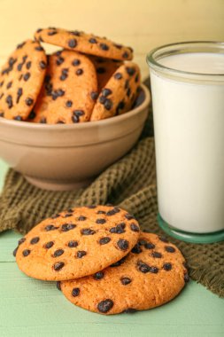Çikolata parçacıklı kurabiyeler ve masada bir bardak süt.