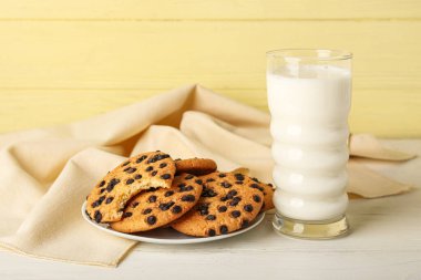 Çikolata parçacıklı kurabiyeler ve masada bir bardak süt.