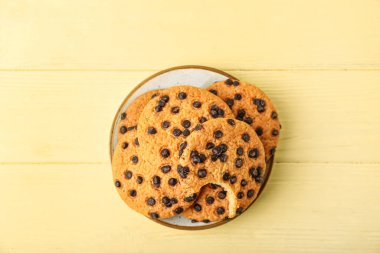 Sarı ahşap arka planda çikolata parçalı lezzetli kurabiyeler.