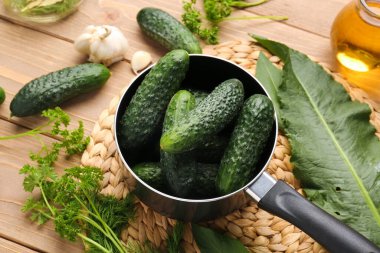 Ahşap arka planda korunması için taze salatalıklı tencere.