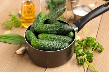 Ahşap arka planda korunması için taze salatalıklı tencere.