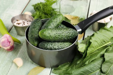 Hafif ahşap arka planda korunması için taze salatalıklı tencere.