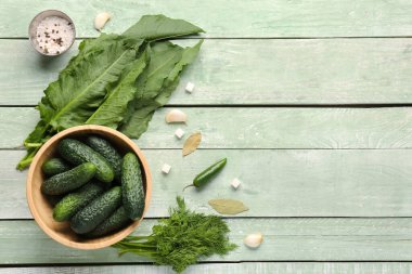 Taze salatalık ve hafif ahşap arka planda korunacak malzemelerle dolu bir kase.