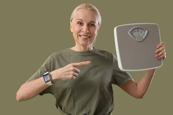 Sporty Mature Woman Pointing Scales Green Background — Stock Photo, Image