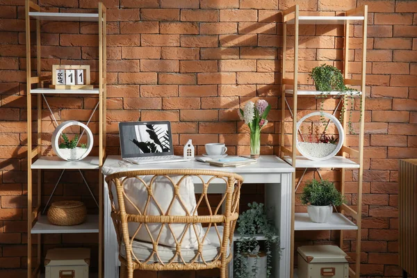 茶色のレンガの壁の近くに現代のラップトップとヒヤシンスの花と快適な職場 — ストック写真