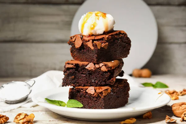 stock image Plate with pieces of tasty chocolate brownie and ice cream on light wooden background