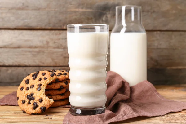 Çikolata parçalı lezzetli kurabiyeler ve ahşap arka planda bir bardak süt.