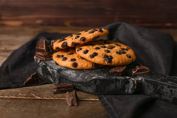 Board of tasty cookies with chocolate chips on wooden background