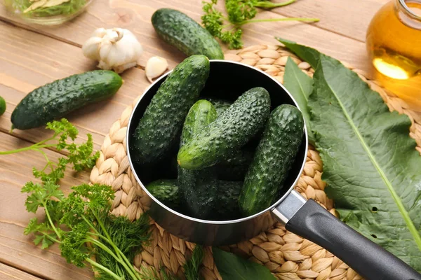 Ahşap arka planda korunması için taze salatalıklı tencere.