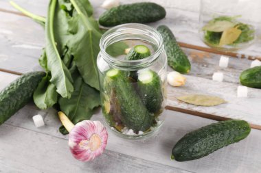 Hafif ahşap masada korunması için taze salatalıklı kavanoz.