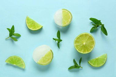 Taze kireç ve buzda donmuş dilimler ve mavi arka planda nane şekeri.