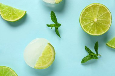 Taze kireç ve buzda donmuş dilimler ve mavi arka planda nane şekeri.