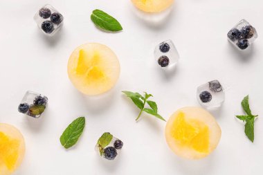 Taze portakal ve böğürtlen parçaları hafif arka planda buzun içinde donmuş.