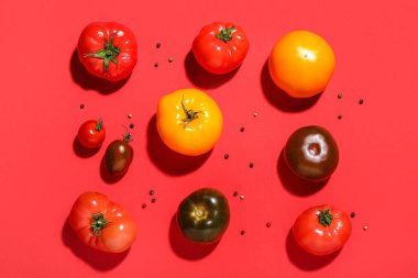 Farklı taze domatesler ve kırmızı arka planda biber.