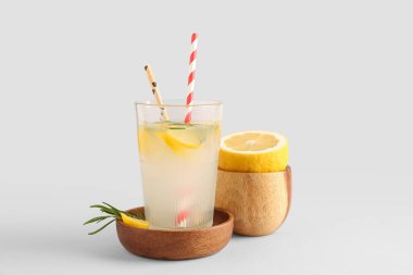 Gri arka planda taze limonata olan bir kase ve cam.