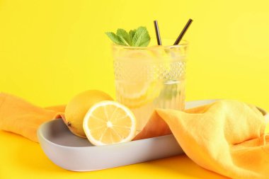 Sarı zemin üzerinde taze limonata olan tabak ve cam.