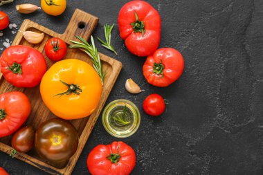 Siyah zemin üzerinde farklı taze domatesler olan tahta.