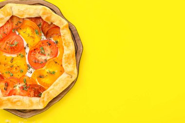 Sarı arka planda leziz domates galetesi olan tahta.