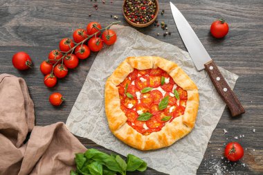 Lezzetli domates galeti ve ahşap arka planda fesleğen içeren kağıt fırını.