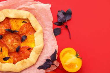 Lezzetli domates galetesi ve kırmızı arka planda fesleğen içeren kağıt fırını.