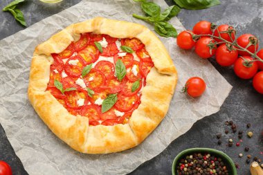 Lezzetli domates galeti ve gri arka planda fesleğen içeren kağıt fırını.