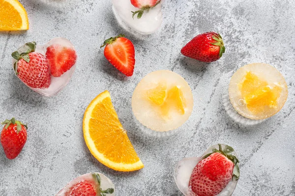 stock image Fresh orange and strawberry frozen in ice on grunge background