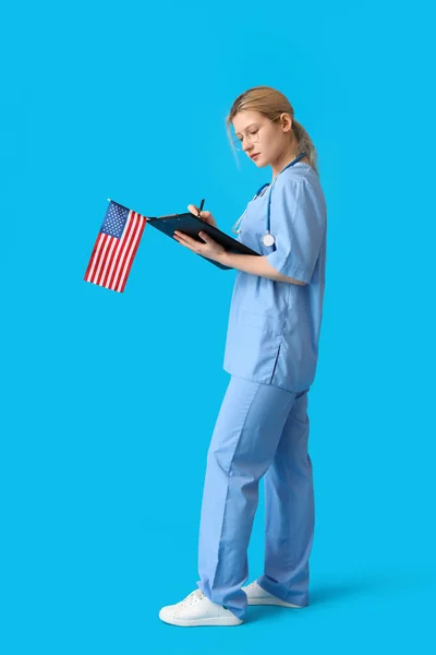 Vrouwelijke Arts Met Usa Vlag Schrijven Klembord Blauwe Achtergrond — Stockfoto