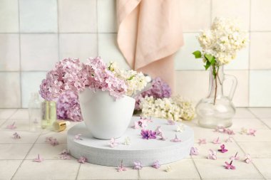 Beyaz fayansın yanında duran güzel kokulu leylak çiçekleri.