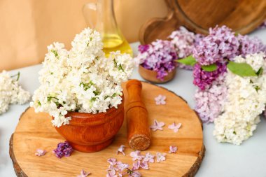 Turuncu duvarın yanındaki beyaz masada güzel leylak çiçekleri olan havan topu