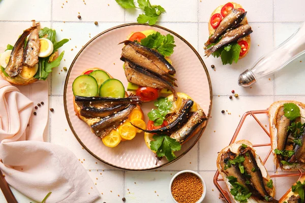 stock image Plate of tasty sandwiches with canned smoked sprats on white tile background