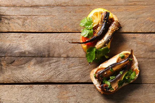 Stock image Tasty sandwiches with canned smoked sprats on wooden background