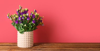 Kırmızı duvarın yanındaki masada güzel Eustoma çiçekleri olan vazo. Tasarım için pankart