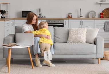 Anne ve küçük oğlu evde kanepede kucaklaşıyorlar.