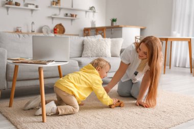 Little boy playing with toy car and his mother at home