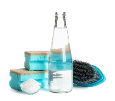 Beyaz arka planda bir şişe sirke, kabartma tozu, fırça ve sünger.