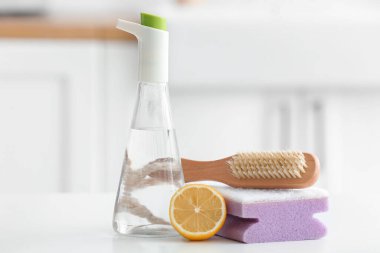 Masada bir şişe sirke, sünger, fırça ve limon.