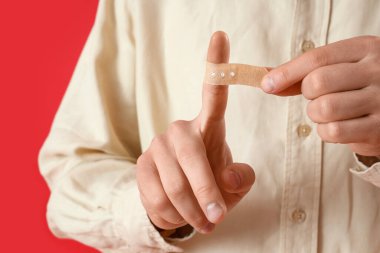 Kırmızı arka planda uygulamalı tıbbi yaması olan genç adam, yakın plan.