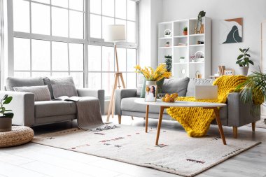 Büyük pencerenin yanında rahat koltukları olan parlak oturma odasının içinde.