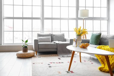 Büyük pencerenin yanında rahat koltukları olan parlak oturma odasının içinde.