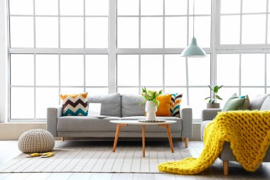 Büyük pencerenin yanında rahat kanepeleri ve kahve masası olan parlak bir oturma odası.