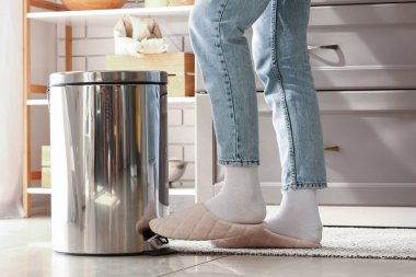 Modern mutfakta kadın ayağıyla çöp tenekesi açıyor.
