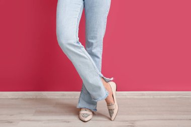 Kırmızı duvarın yanındaki şık kotlu genç kadın.