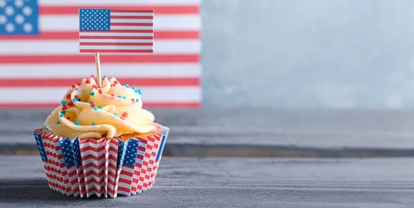 stock image Tasty patriotic cupcake on wooden table against USA flag. American Independence Day