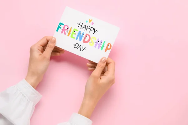 ピンクの背景に友情の日のためのグリーティングカードを保持する女性の手 — ストック写真