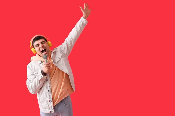 Junger Mann Mit Kopfhörer Und Mikrofon Singt Auf Rotem Hintergrund — Stockfoto