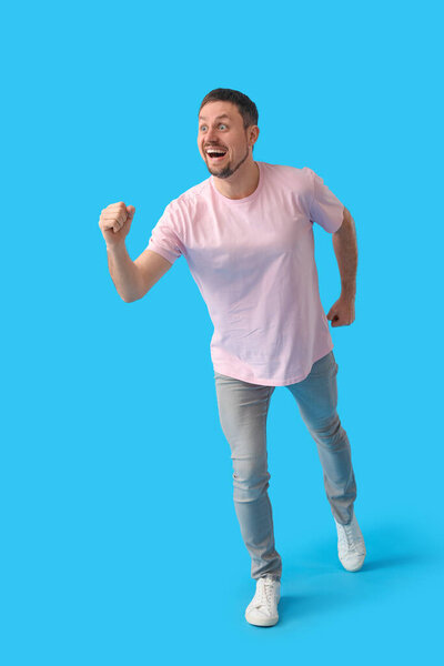 Handsome man in t-shirt running on blue background